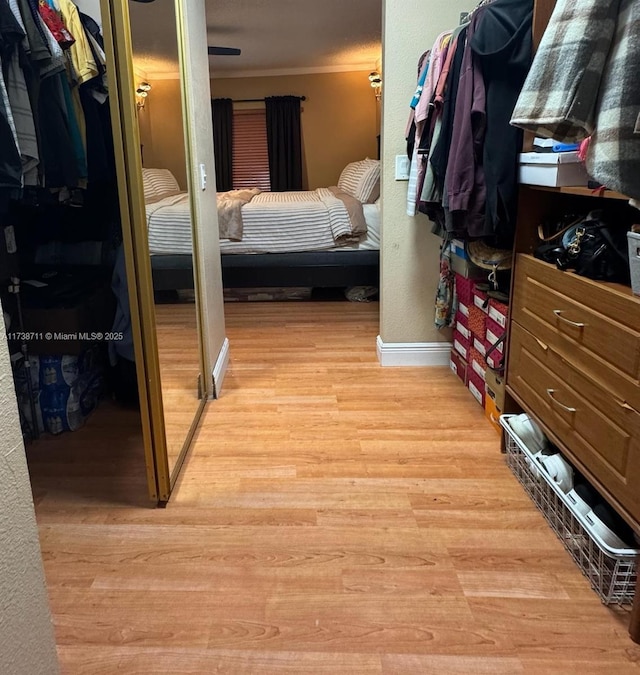 bedroom featuring crown molding, light wood-type flooring, and a closet