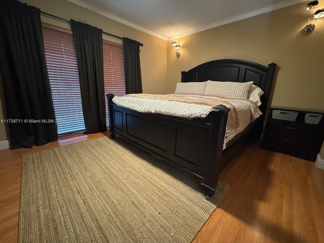 bedroom with wood-type flooring, ornamental molding, and a textured ceiling