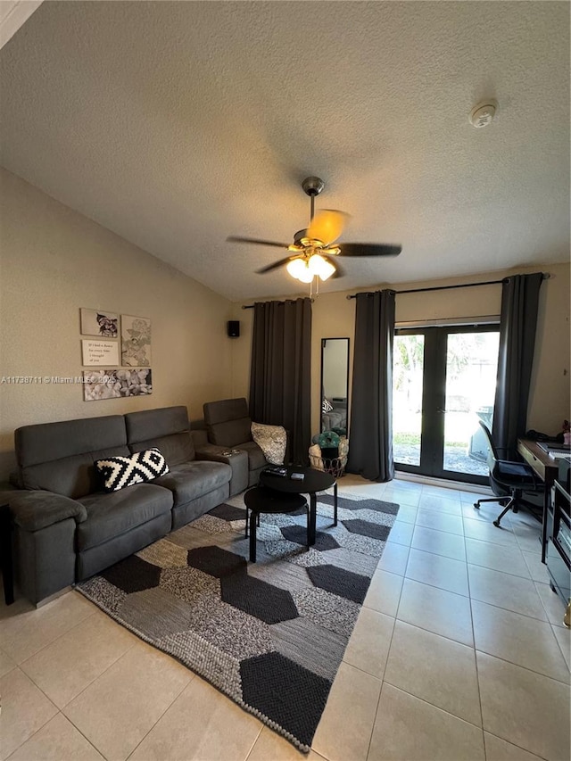 living room with a textured ceiling, vaulted ceiling, ceiling fan, and light tile patterned flooring