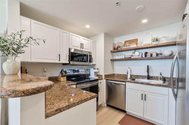 kitchen featuring sink, light hardwood / wood-style flooring, stainless steel appliances, white cabinets, and kitchen peninsula