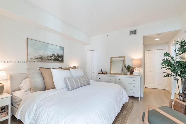 bedroom with multiple closets and light hardwood / wood-style flooring