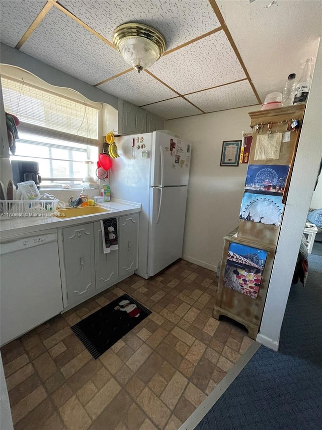 kitchen with white cabinetry, white appliances, and a drop ceiling