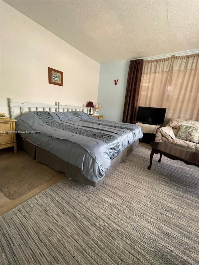 bedroom featuring vaulted ceiling, carpet floors, and a textured ceiling