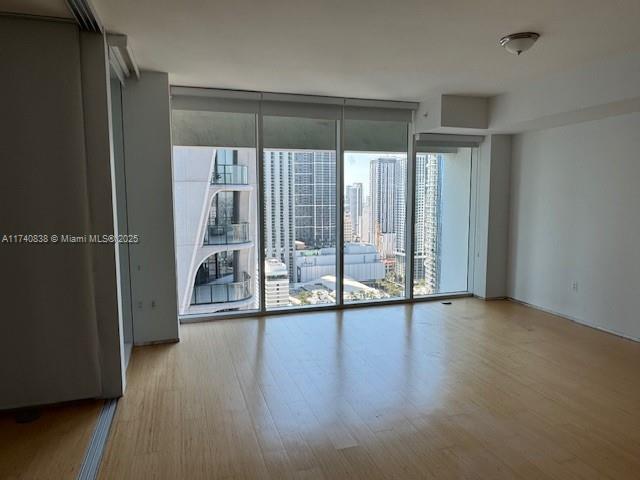 spare room with expansive windows and light hardwood / wood-style flooring