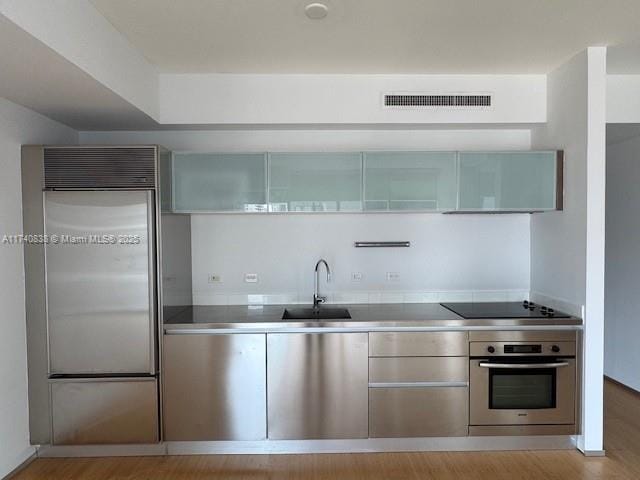 kitchen featuring stainless steel counters, appliances with stainless steel finishes, sink, and light hardwood / wood-style flooring