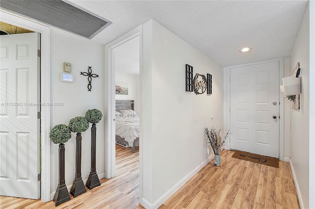 hall featuring a textured ceiling and light wood-type flooring