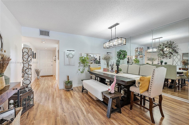 dining room featuring a notable chandelier, a textured ceiling, and light wood-type flooring