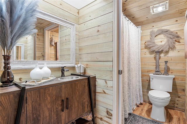 bathroom featuring toilet, hardwood / wood-style floors, vanity, and wood walls