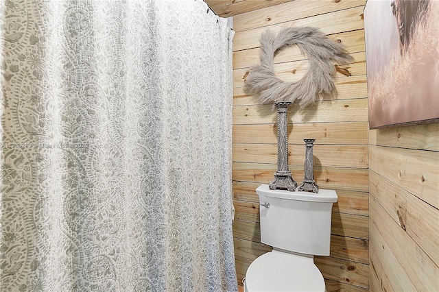 bathroom featuring wooden walls and toilet