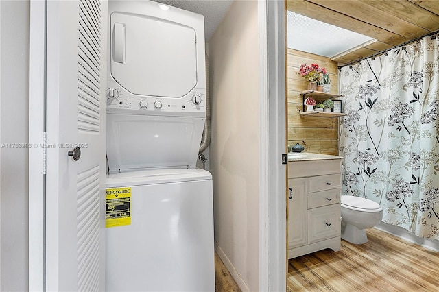 washroom featuring stacked washing maching and dryer and light hardwood / wood-style flooring