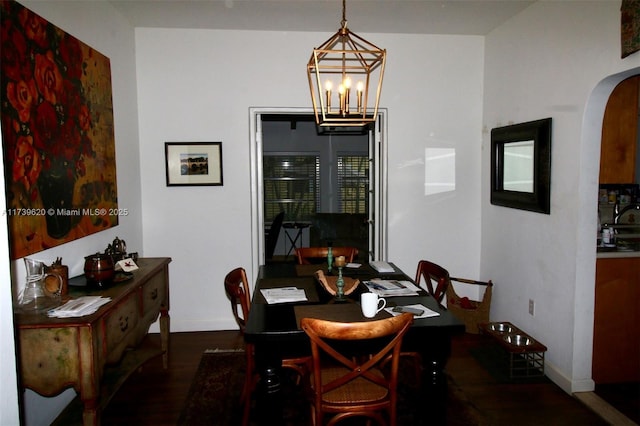 dining area with dark wood-type flooring and a notable chandelier