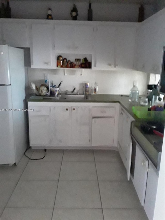 kitchen with tasteful backsplash, light tile patterned floors, white fridge, and white cabinets