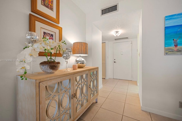 hallway with light tile patterned floors and a textured ceiling