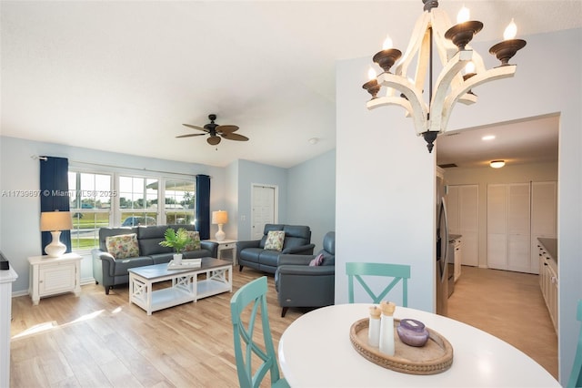 dining area featuring vaulted ceiling, ceiling fan with notable chandelier, and light hardwood / wood-style floors