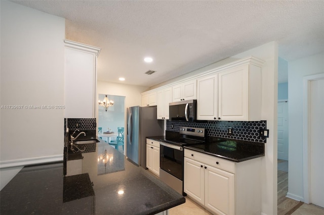 kitchen with sink, white cabinetry, stainless steel appliances, tasteful backsplash, and a notable chandelier