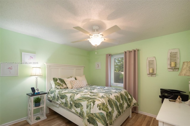 bedroom featuring ceiling fan, wood-type flooring, and a textured ceiling