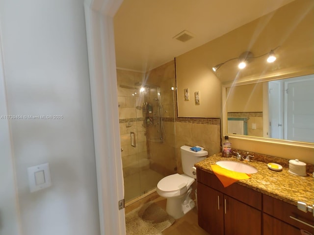 bathroom featuring a shower with door, vanity, tile walls, and toilet