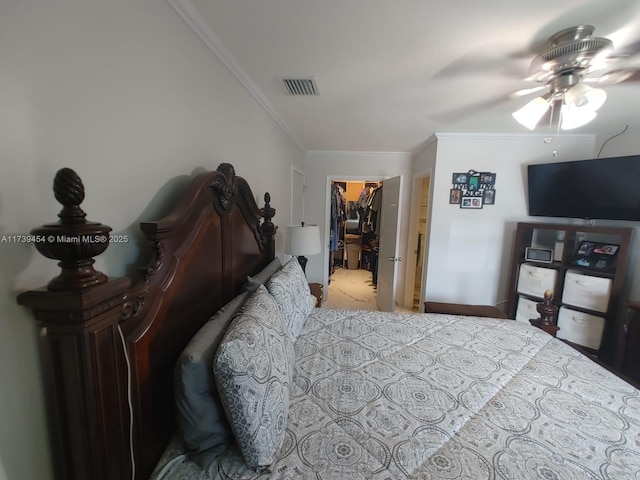 carpeted bedroom featuring crown molding, a walk in closet, ceiling fan, and a closet