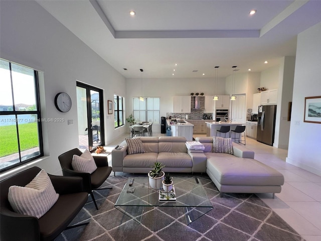 tiled living room featuring french doors, a raised ceiling, a water view, and a high ceiling