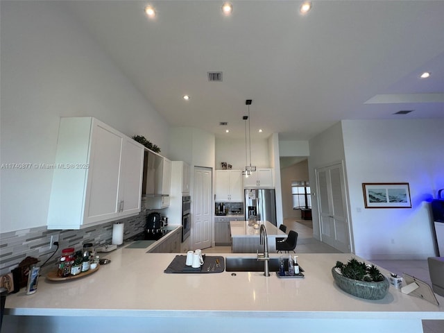 kitchen with appliances with stainless steel finishes, decorative light fixtures, tasteful backsplash, white cabinetry, and sink