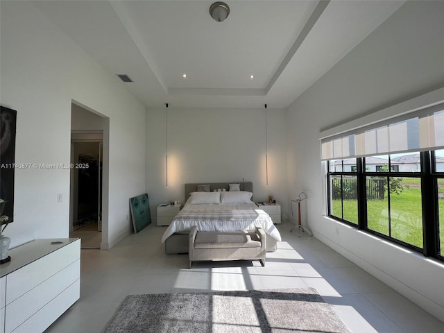 bedroom featuring light tile patterned floors, a tray ceiling, and a high ceiling