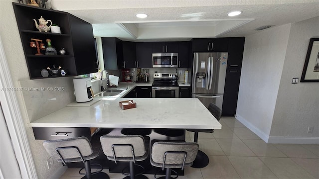 5051 NE 6th Ave, Deerfield Beach, FL 33064 - kitchen with appliances with stainless steel finishes, a breakfast bar, sink, kitchen peninsula, and a textured ceiling