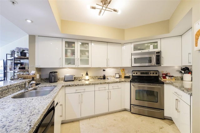 kitchen featuring white cabinetry, sink, light stone counters, and appliances with stainless steel finishes