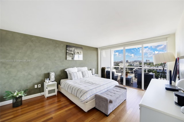 bedroom featuring dark wood-type flooring and a wall of windows