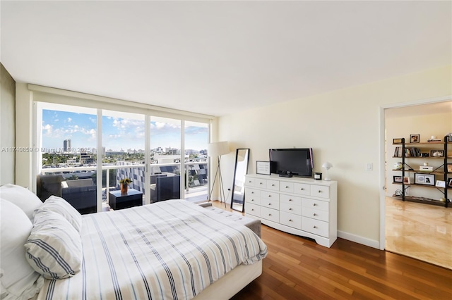 bedroom featuring wood-type flooring, access to exterior, and a wall of windows