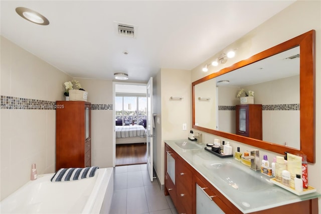 bathroom with tile patterned floors, a bath, vanity, and tile walls