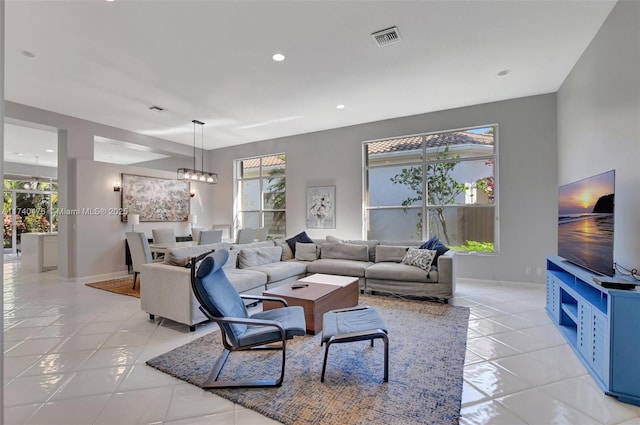 living room featuring light tile patterned flooring, plenty of natural light, and an inviting chandelier