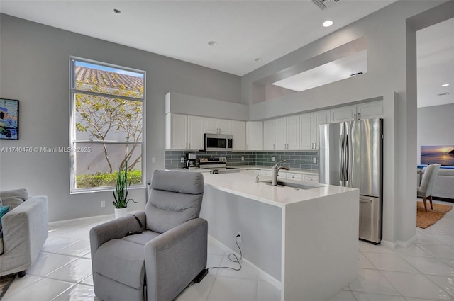 kitchen with sink, appliances with stainless steel finishes, a wealth of natural light, decorative backsplash, and white cabinets