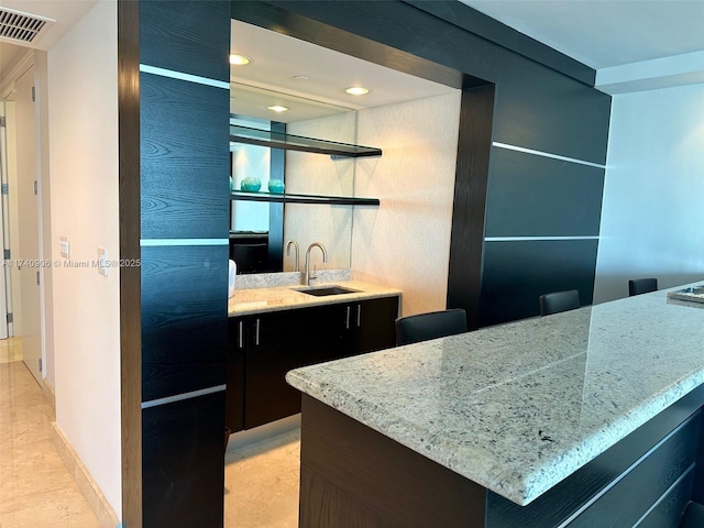 kitchen featuring light stone counters and sink