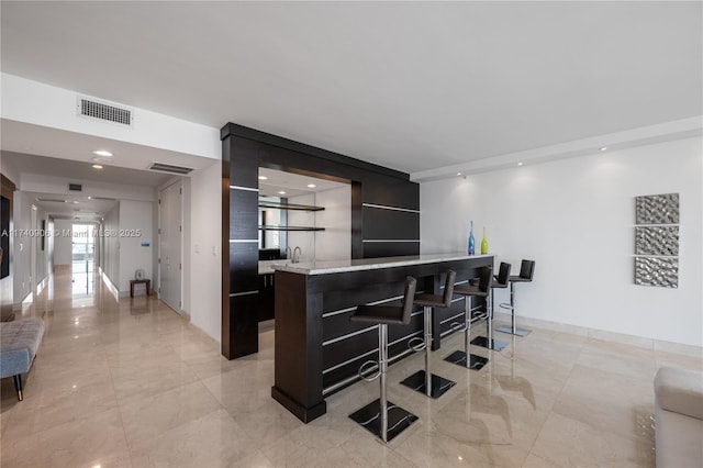 kitchen with light countertops, modern cabinets, a kitchen bar, and visible vents