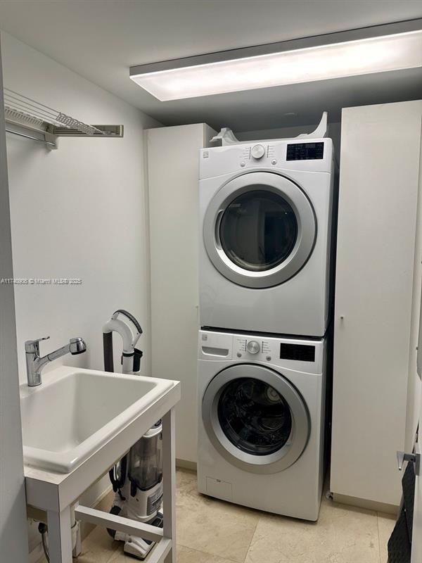 laundry area featuring stacked washer / dryer and sink