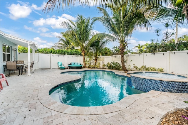 view of pool with a patio, pool water feature, and an in ground hot tub