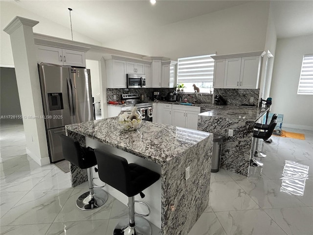 kitchen with tasteful backsplash, vaulted ceiling, appliances with stainless steel finishes, a kitchen breakfast bar, and dark stone counters