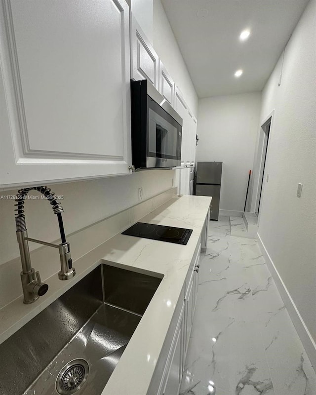 kitchen featuring stainless steel appliances, light stone countertops, sink, and white cabinets