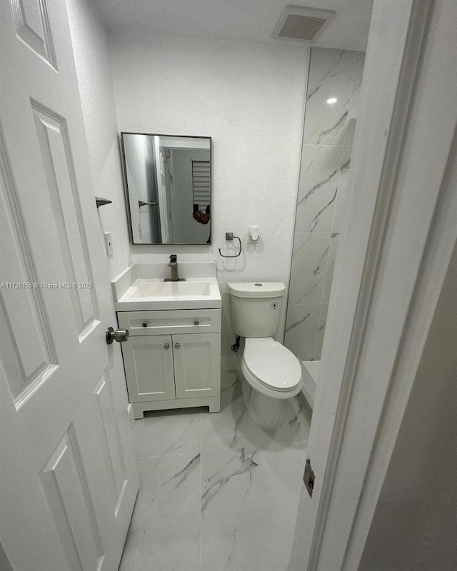 bathroom featuring vanity, toilet, and tiled shower