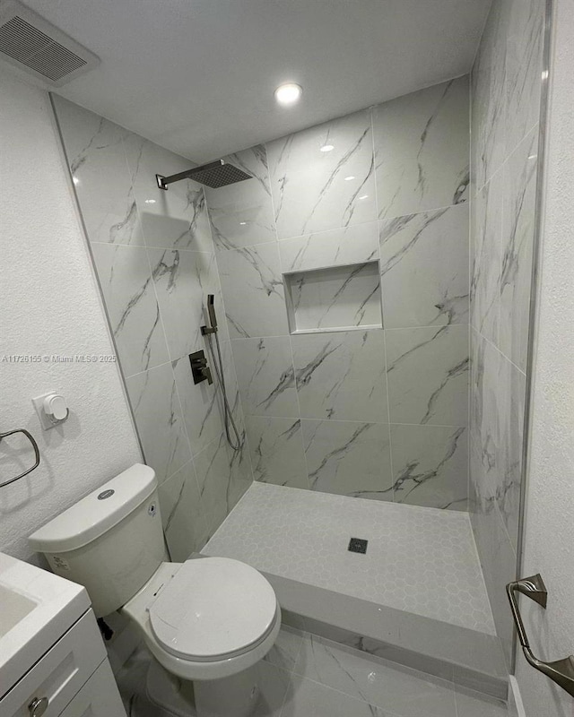 bathroom featuring tiled shower, vanity, and toilet