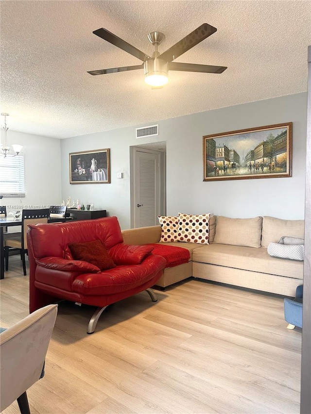 living room featuring hardwood / wood-style floors, a textured ceiling, and ceiling fan