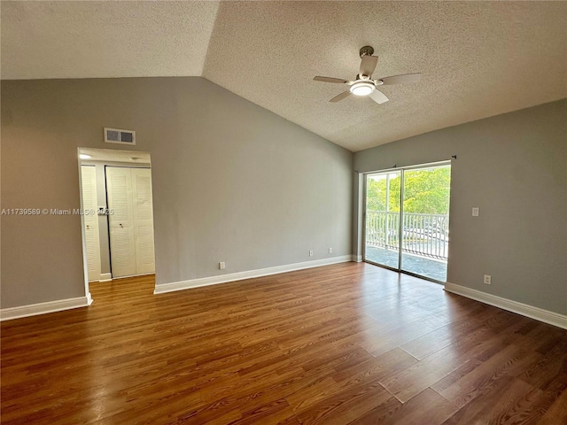 empty room with lofted ceiling, a textured ceiling, dark hardwood / wood-style floors, and ceiling fan