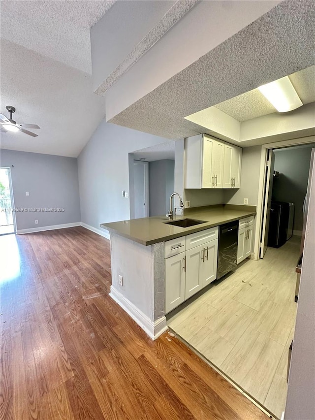 kitchen featuring sink, black dishwasher, kitchen peninsula, light hardwood / wood-style floors, and white cabinets