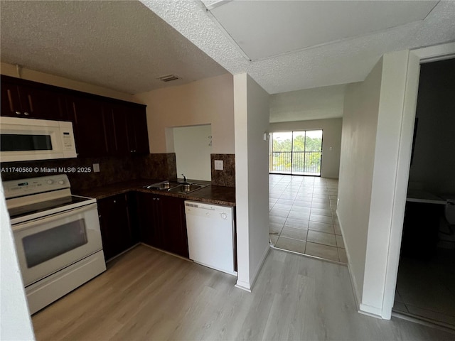 kitchen featuring sink, backsplash, white appliances, a textured ceiling, and light hardwood / wood-style flooring