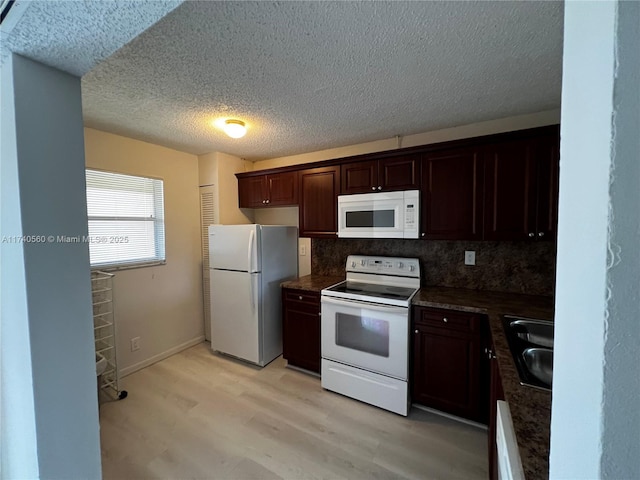 kitchen with sink, dark brown cabinets, light hardwood / wood-style flooring, white appliances, and backsplash