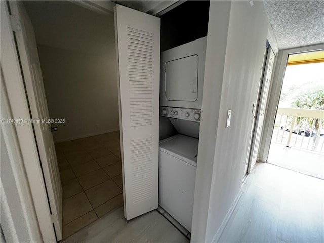 laundry area with a textured ceiling and stacked washer / dryer