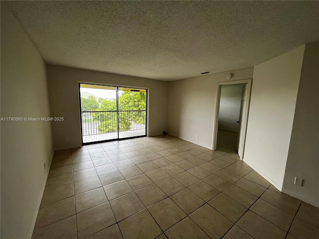 spare room with a textured ceiling and light tile patterned flooring