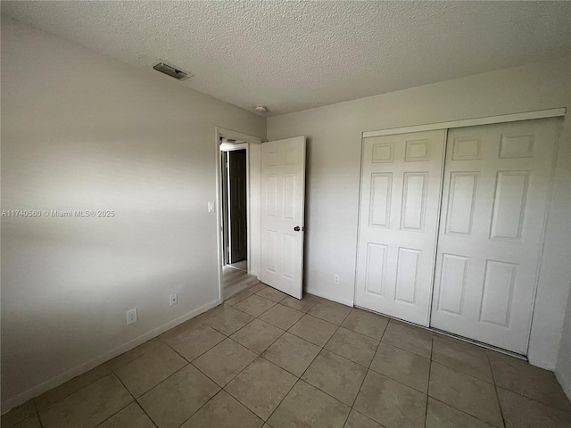 unfurnished bedroom with light tile patterned floors, a closet, and a textured ceiling