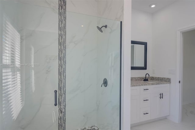 bathroom featuring a shower with door and vanity