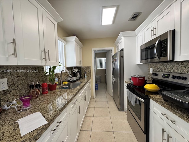 kitchen with appliances with stainless steel finishes, sink, white cabinets, and dark stone counters